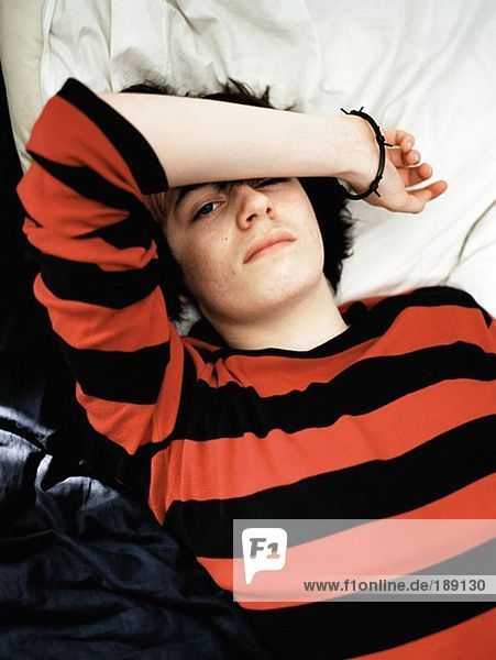 Teenager-Junge auf dem Bett liegend