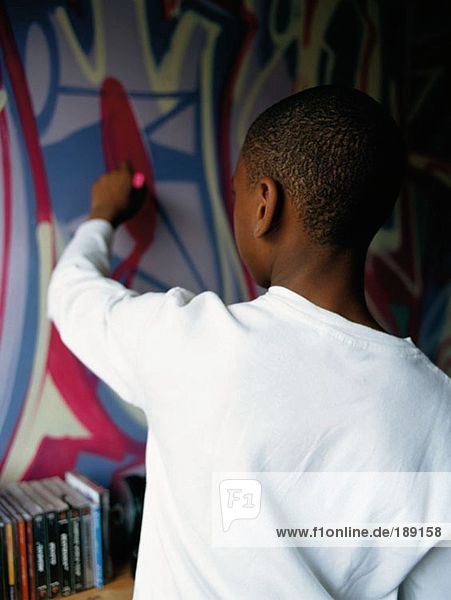 Junge malt Graffiti an der Wand