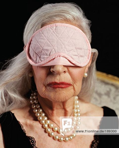 Ältere erwachsene Frau mit rosa Augenmaske