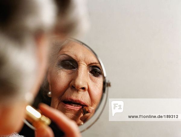 Eine ältere Frau  die Lippenstift aufträgt.