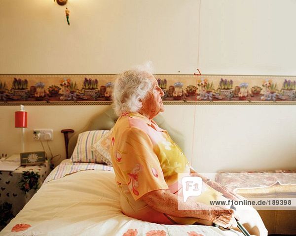 Ältere Frau auf dem Bett sitzend
