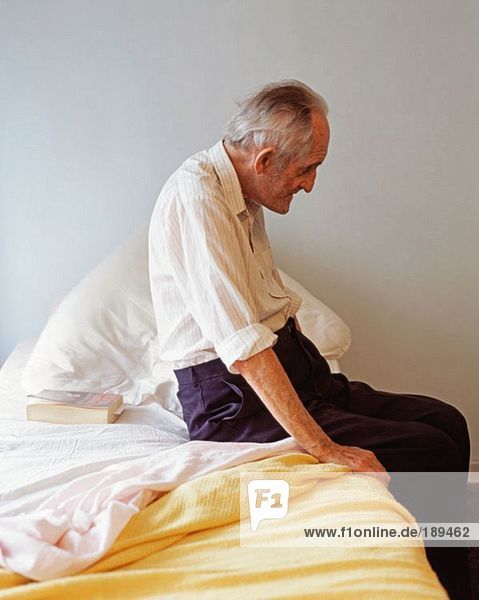 Älterer Mann auf seinem Bett sitzend