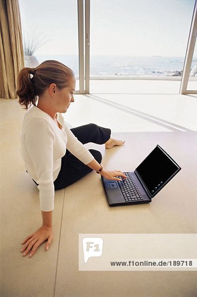Frau mit Laptop auf dem Wohnzimmerboden