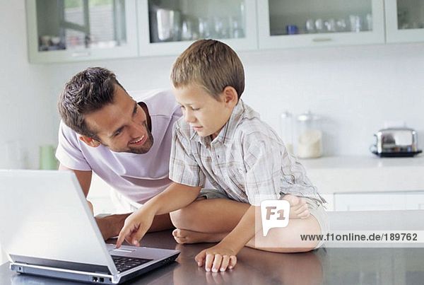 Vater zeigt Sohn  wie man einen Laptop benutzt