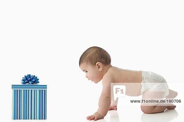 Baby krabbelt auf Geschenkkarton zu