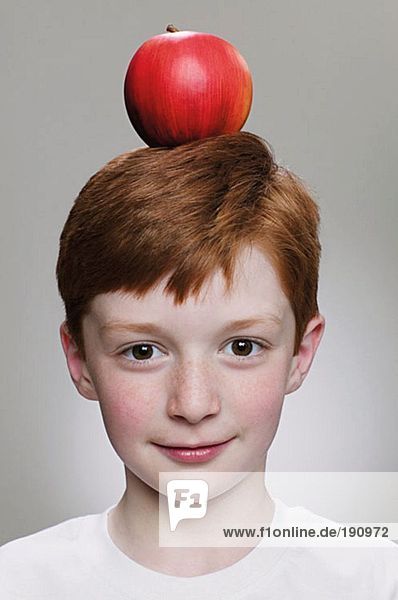 Junge  der einen Apfel auf dem Kopf balanciert.