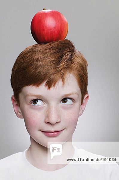 Junge  der einen Apfel auf dem Kopf balanciert.
