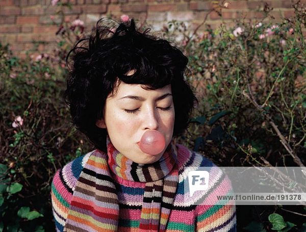 Woman blowing a bubble gum bubble