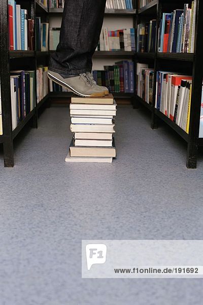 Stehende Person auf Büchern in der Bibliothek