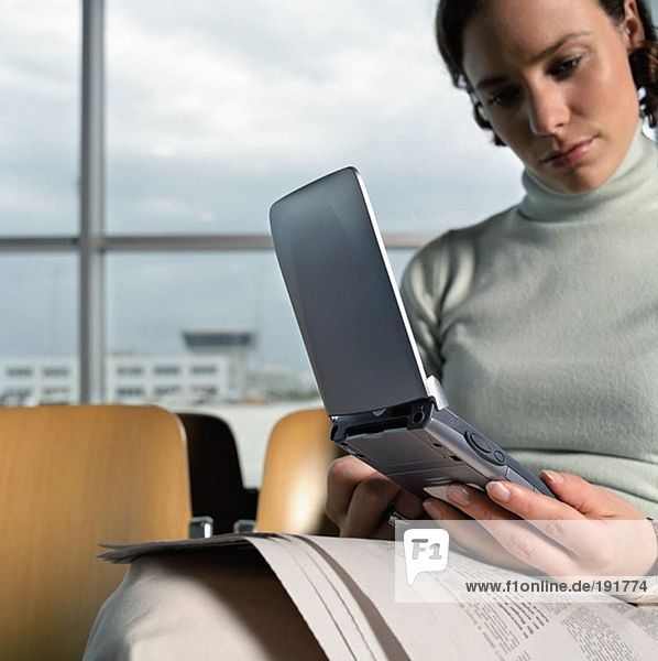 Woman using palmtop in departure lounge