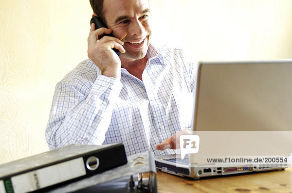 Mid adult man talking on mobile phone and smiling