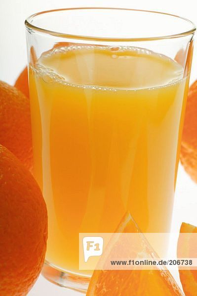 Orangensaft im Glas zwischen Orangen (Close up)