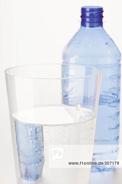 Mineralwasser im Glas vor Plastikflasche