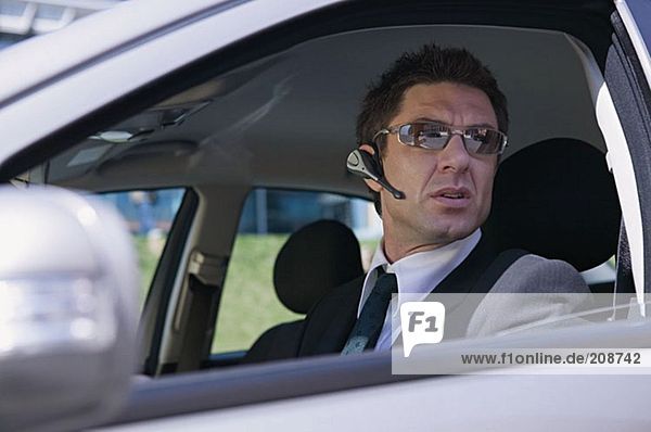 Businessman in car wearing headset