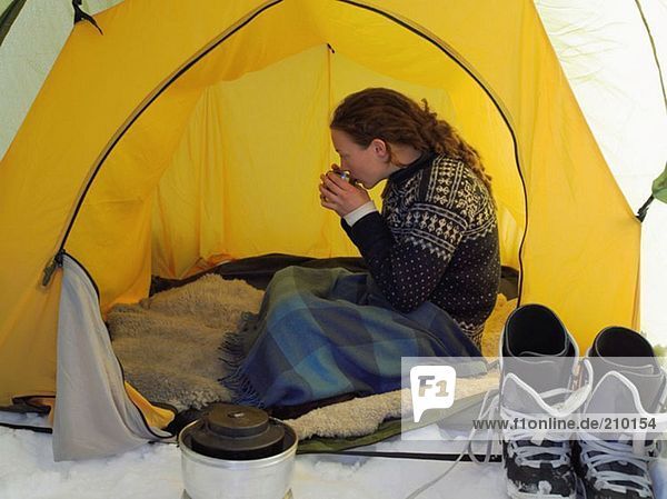 Female skier having a drink in a tent