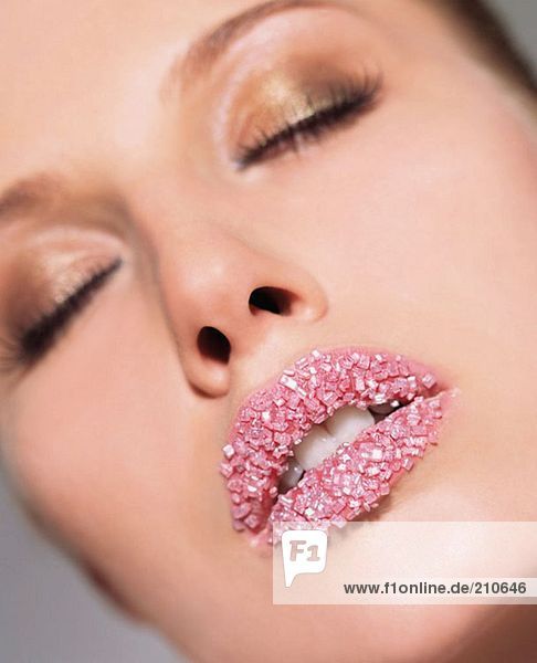 Frau mit rosa Zuckerkristallen auf den Lippen  dem Mund.