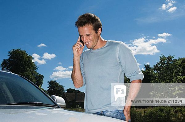 Man in mobile phone by his car