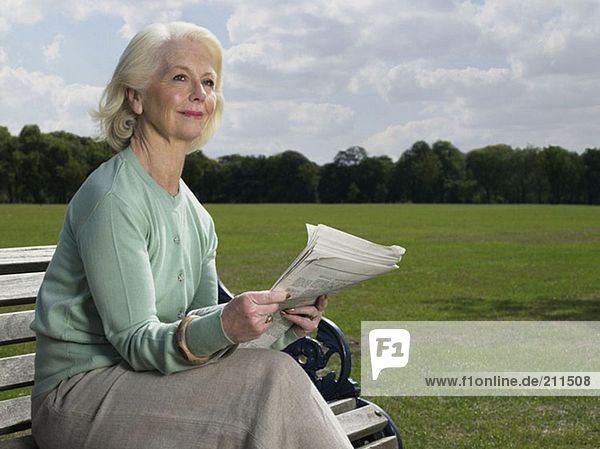 Ältere Frau beim Lesen im Park