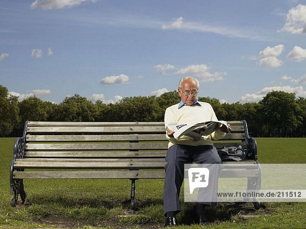 Älterer Mann beim Lesen einer Zeitung im Park