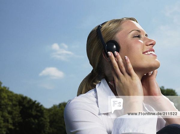 Frau beim Musikhören im Park