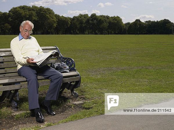 Älterer Mann beim Lesen einer Zeitung im Park