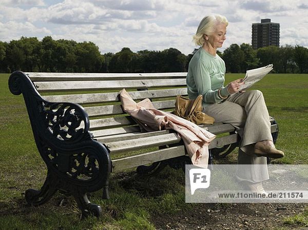 Ältere Frau beim Lesen im Park