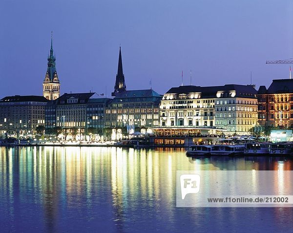 Boats in river with lit up buildings in background  River Alster  Hamburg  Germany