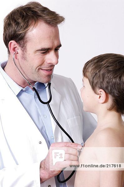 Male doctor examining boy with stethoscope