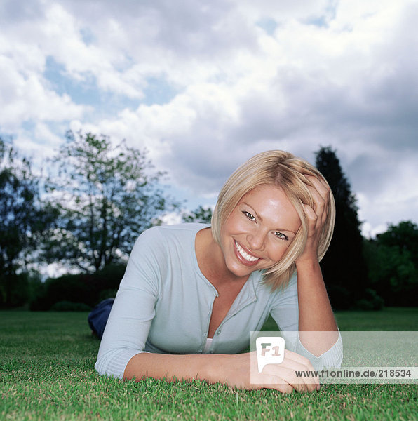 Blonde Frau auf Gras liegend