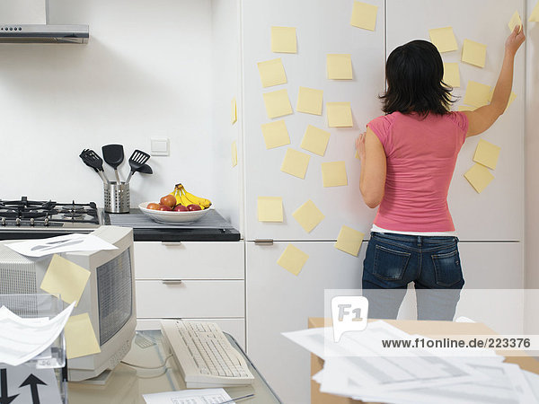 Woman putting up adhesive notes in the kitchen