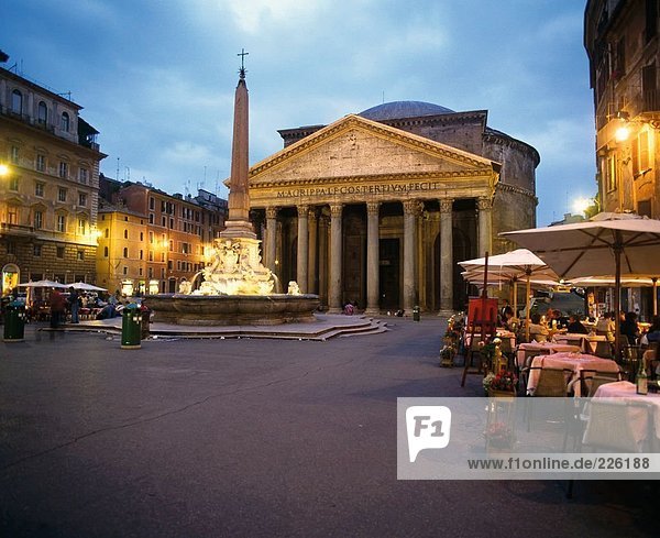 Obelisk lit up near restaurant in city square  Pantheon Rome  Frieze  Italy