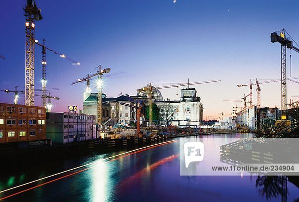 Cranes and building lit up at dusk  Spree River  The Reichstag  Berlin  Germany