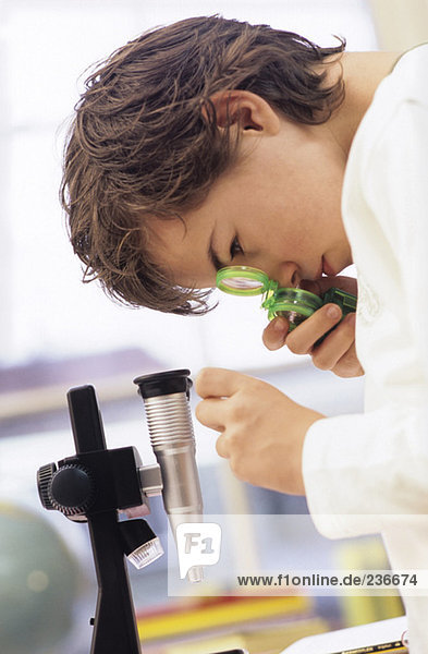 Junge (8-9) schaut durchs Mikroskop