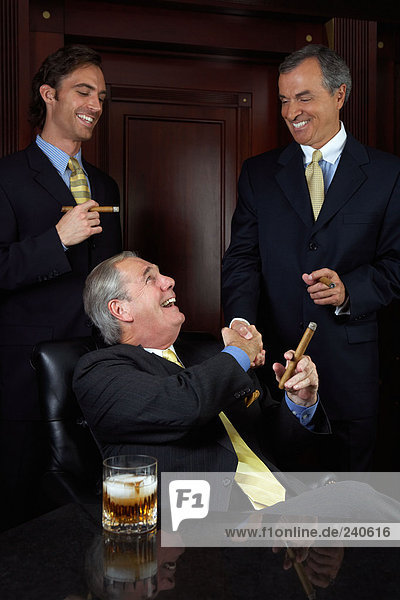 Drei Geschäftsleute feiern mit Zigarren