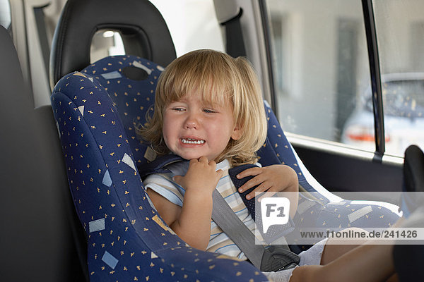 Young girl crying in her car seat