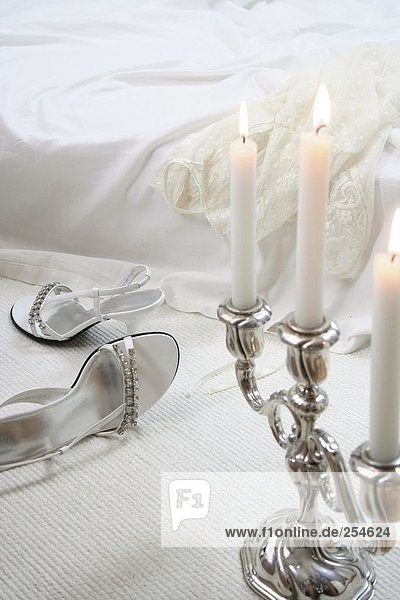 Close-up of lit candles with pair of high heels in background