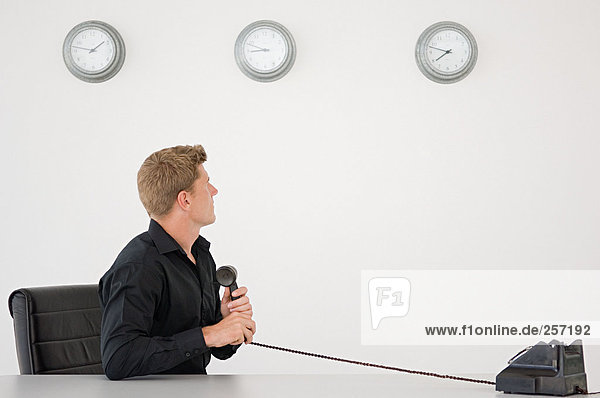 Businessman watching the clock holding telephone