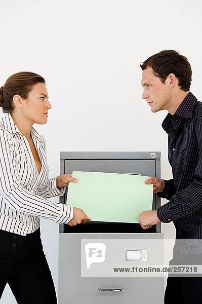 Businessman and businesswoman fighting over file