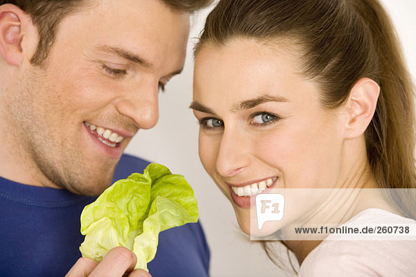 Junges Paar mit Salatblatt  lächelnd  Nahaufnahme