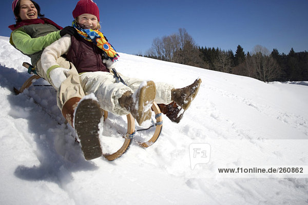 Österreich  Mädchen (6-17) Rodeln auf verschneiter Piste  lächelnd  Tiefblick