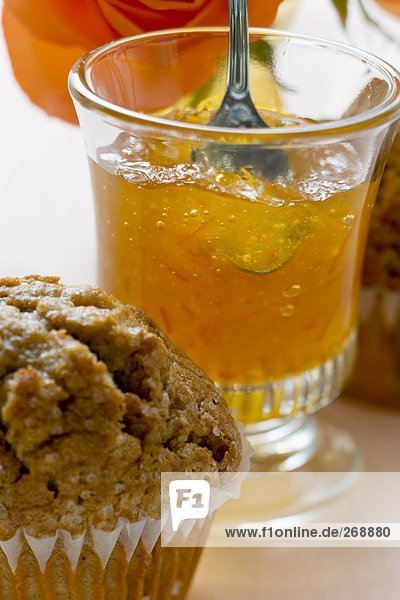 Orangengelee in einem Glas  davor ein Muffin