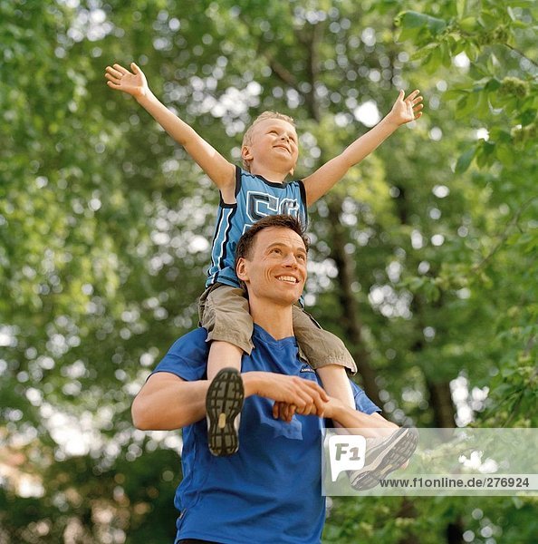 Father with son on the shoulders in a park.