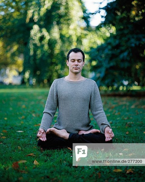 Ein Mann tun Yoga in einem Park.