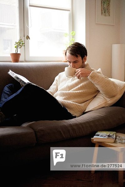 A man that reads in a sofa.