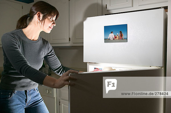 Frau betrachtet Foto auf Kühlschrank