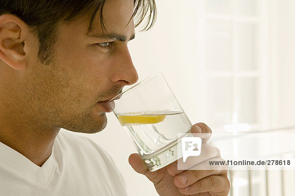 Mann Trinkwasser mit Zitrone