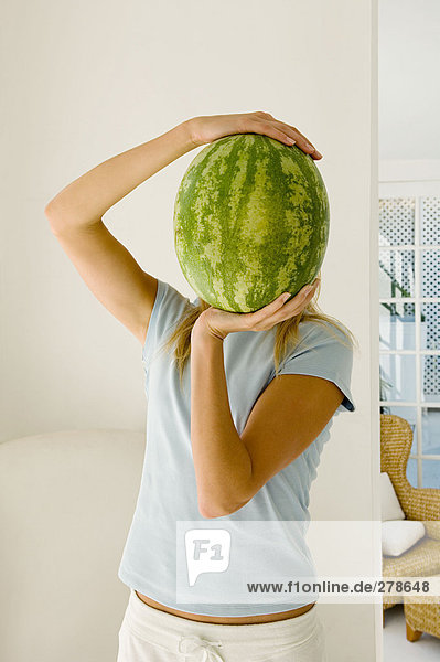 Frau hält Wassermelone über Gesicht