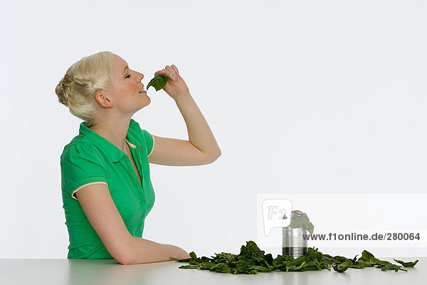 Junge Frau isst Spinat