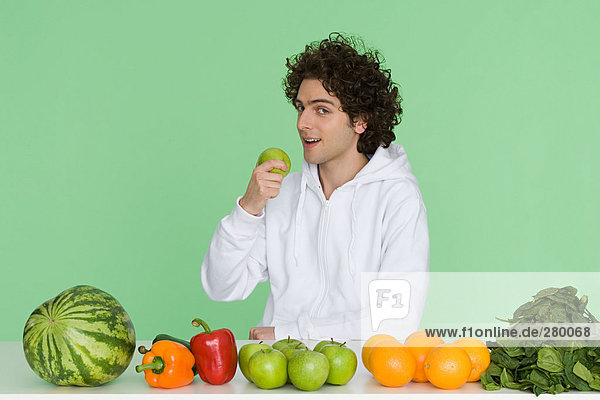 Junger Mann mit Obst und Gemüse auf dem Tisch