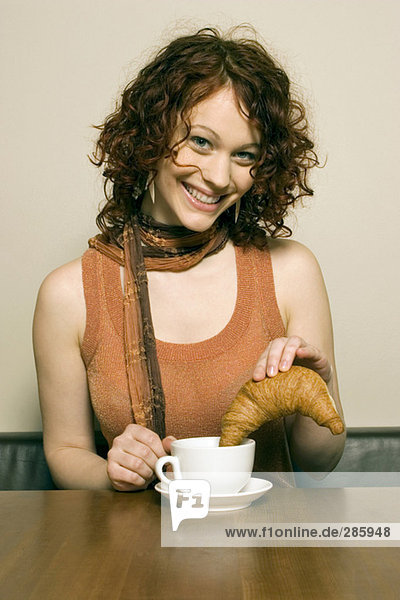 Junge Frau am Tisch sitzend mit Kaffeetasse